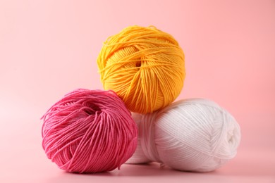 Photo of Different colorful yarns on pink background, closeup