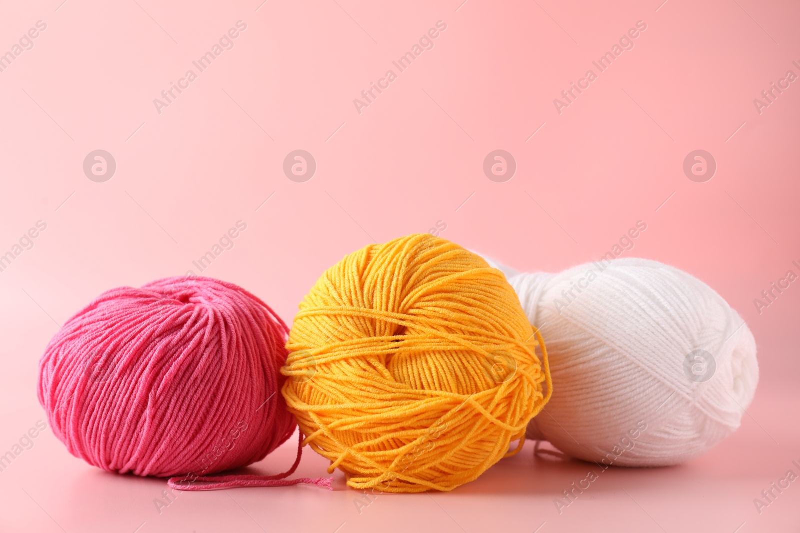 Photo of Different colorful yarns on pink background, closeup. Space for text