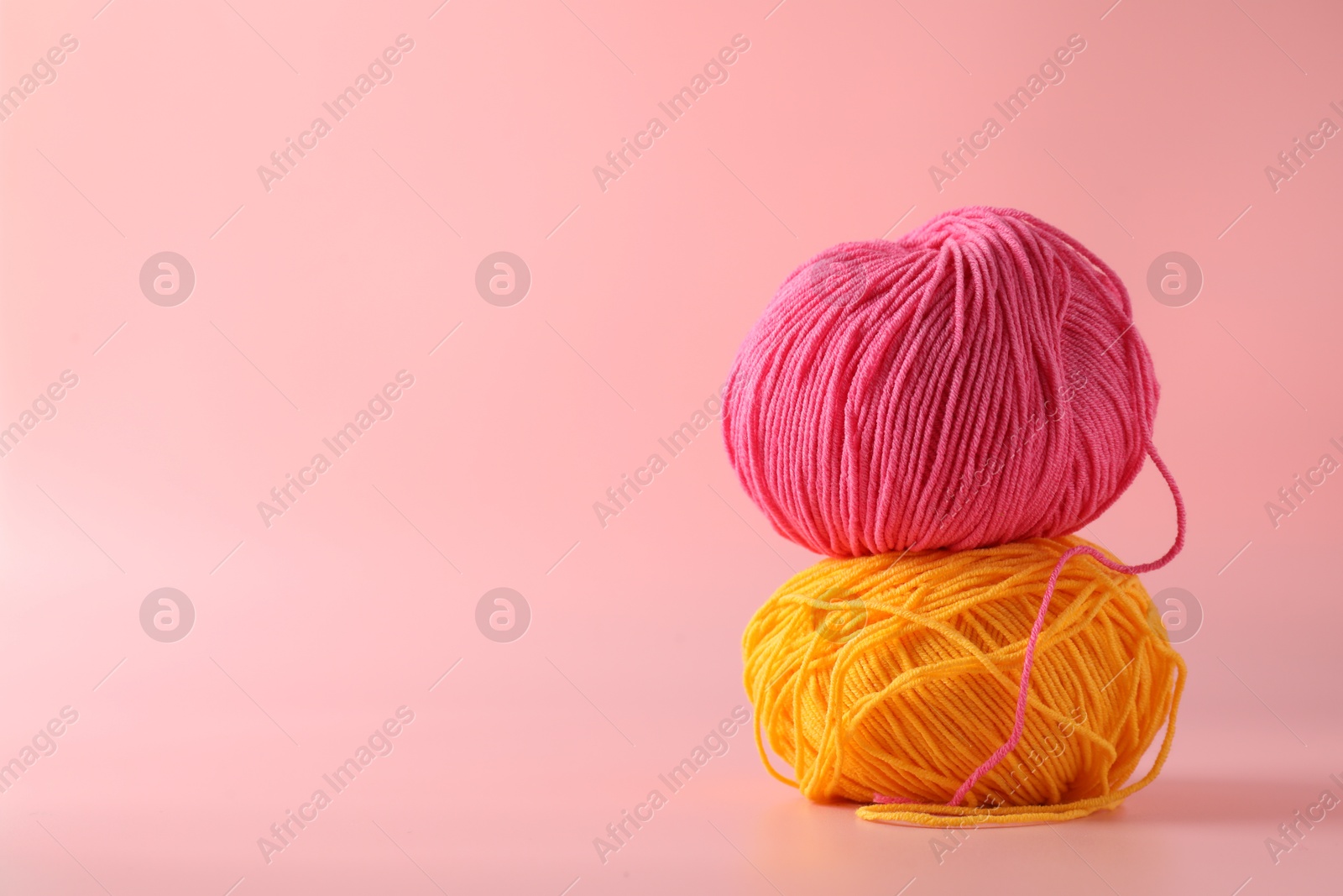 Photo of Colorful yarns on pink background. Space for text