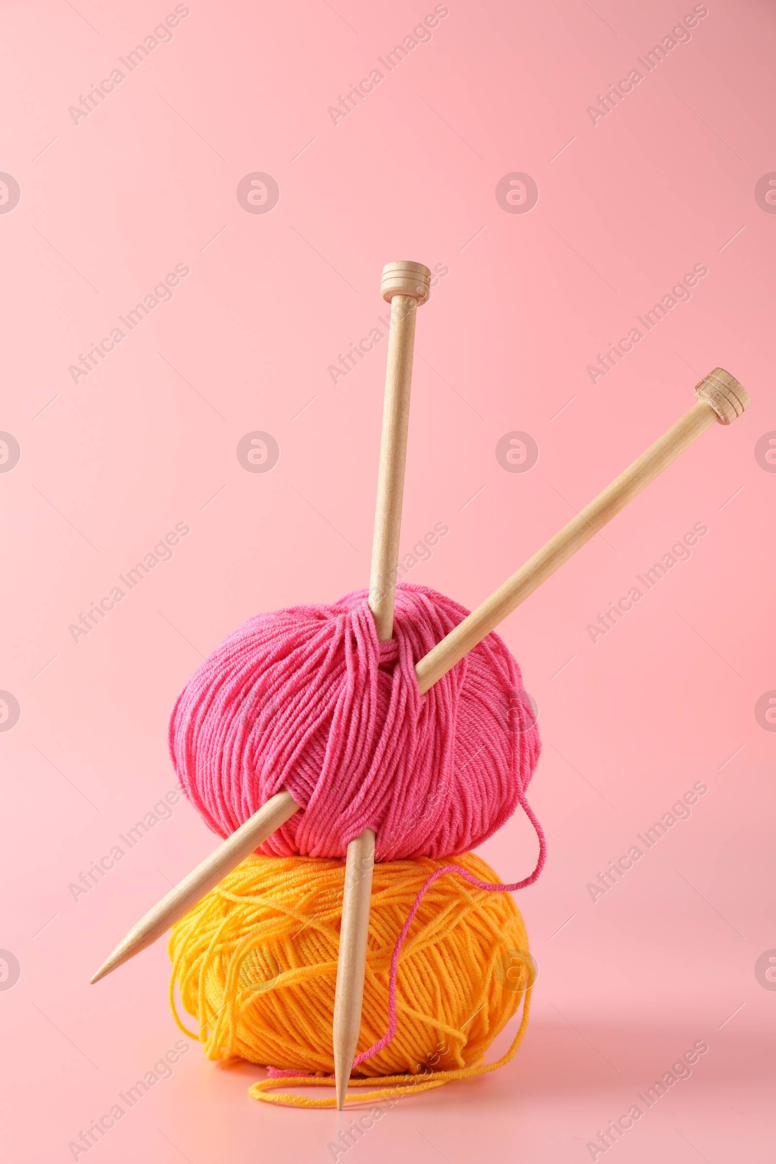 Photo of Colorful yarns and knitting needles on pink background