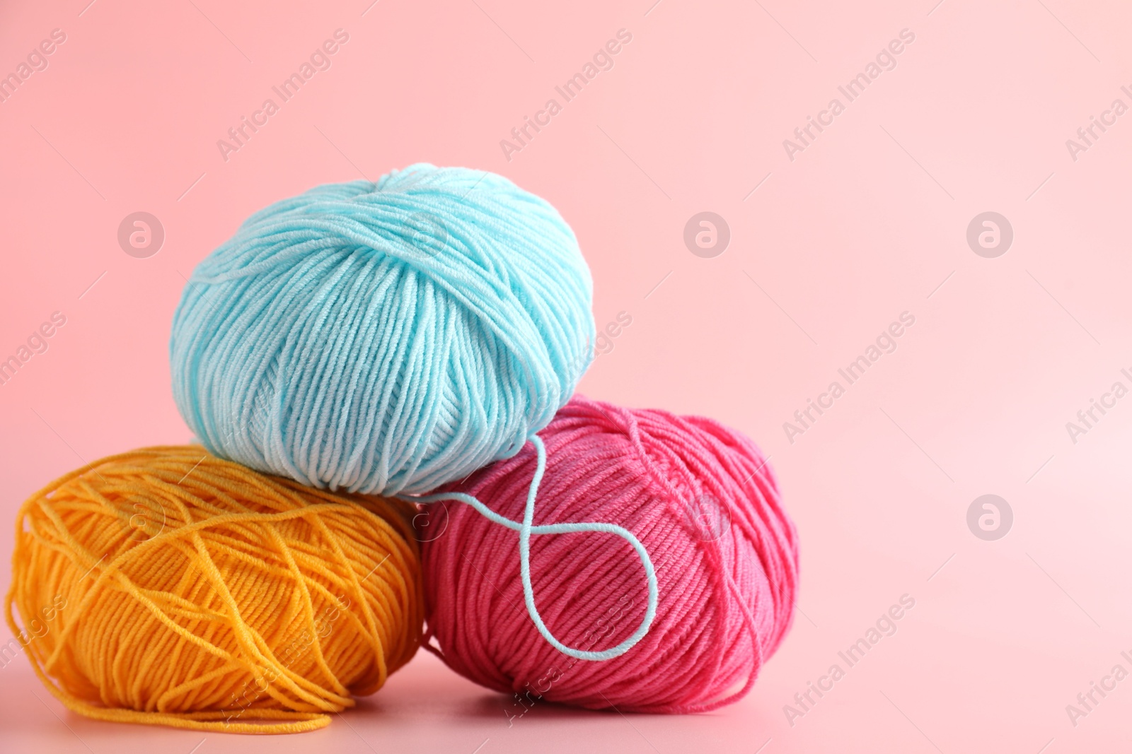 Photo of Different colorful yarns on pink background, closeup. Space for text