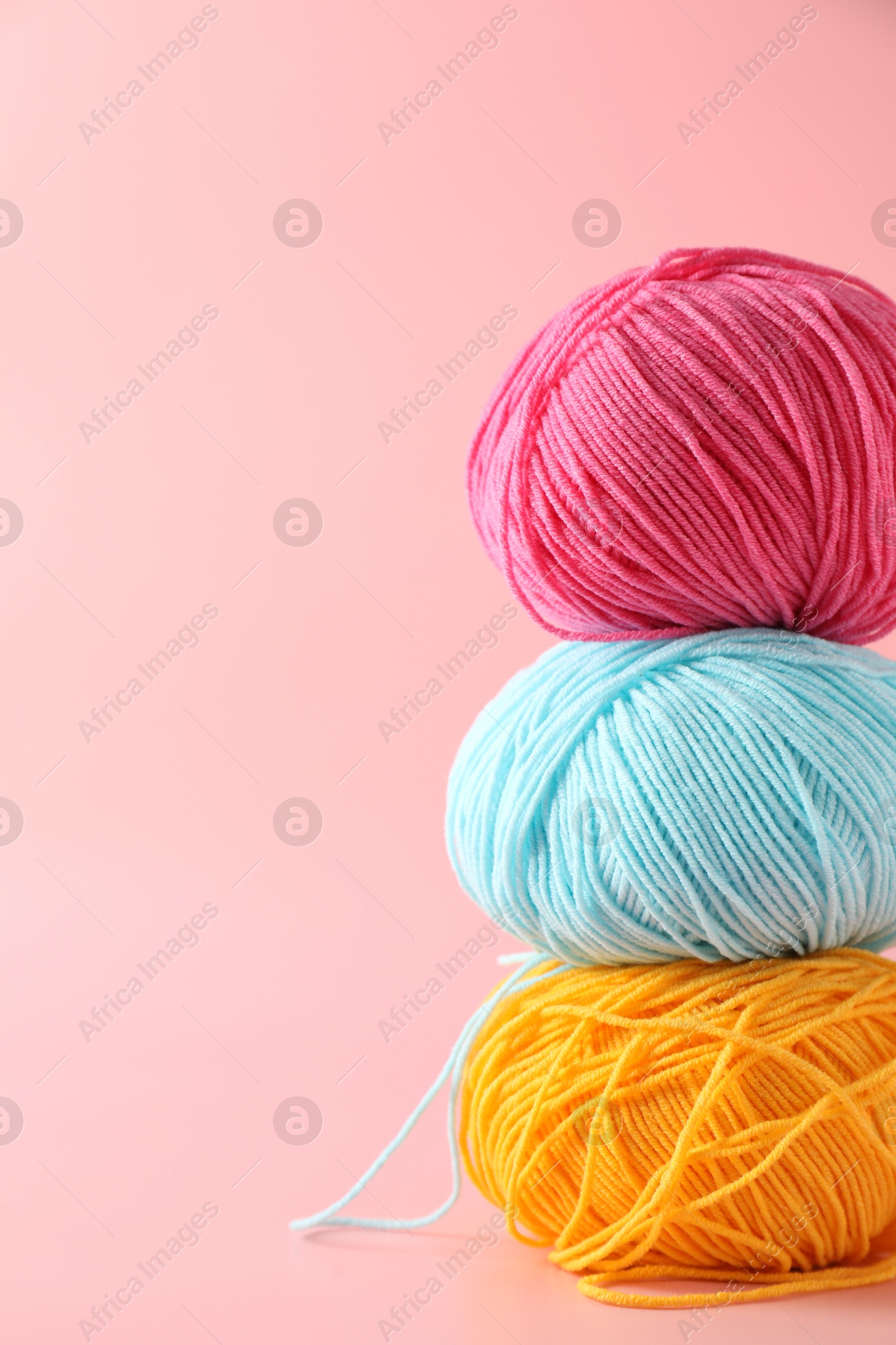 Photo of Stack of colorful yarns on pink background. Space for text