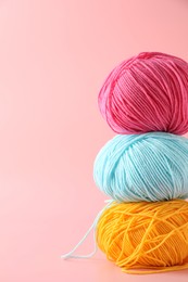 Stack of colorful yarns on pink background. Space for text