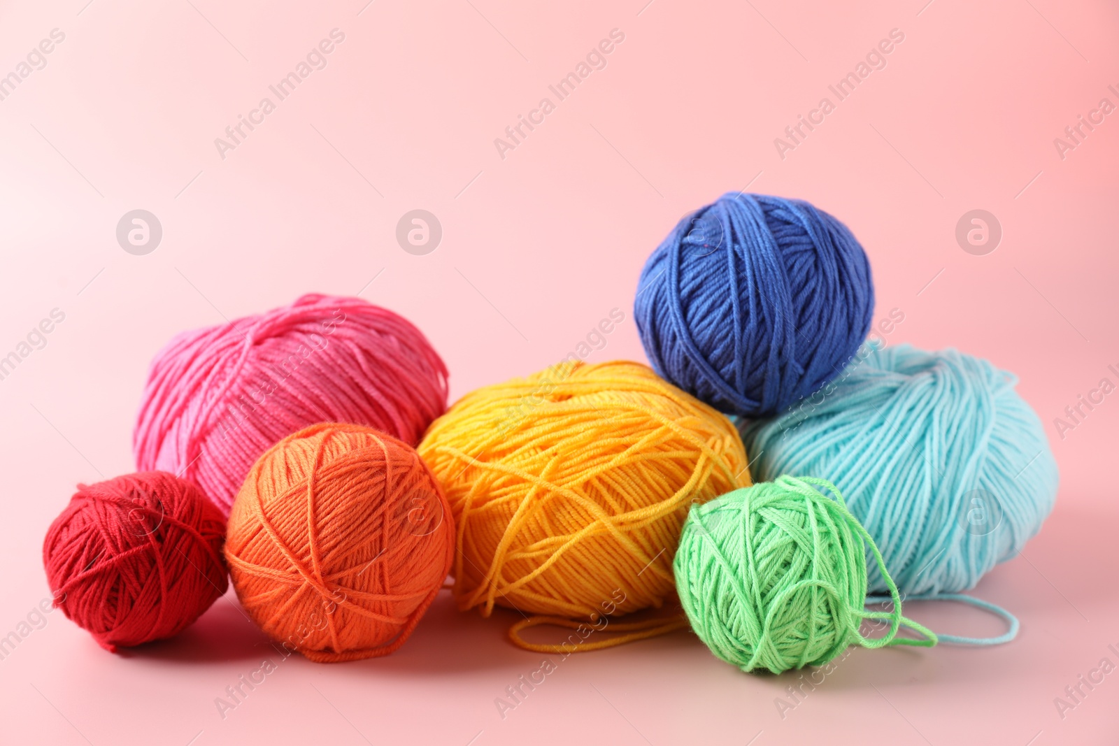 Photo of Pile of different colorful yarns on pink background, closeup