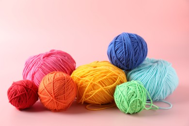 Pile of different colorful yarns on pink background, closeup