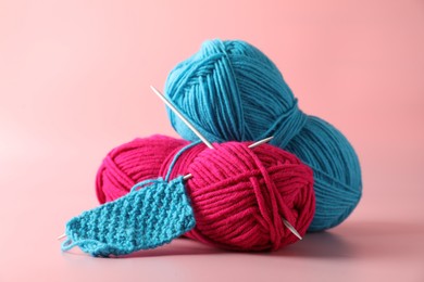 Different yarns, knitting needles and pattern sample on pink background, closeup