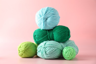 Pile of different colorful yarns on pink background