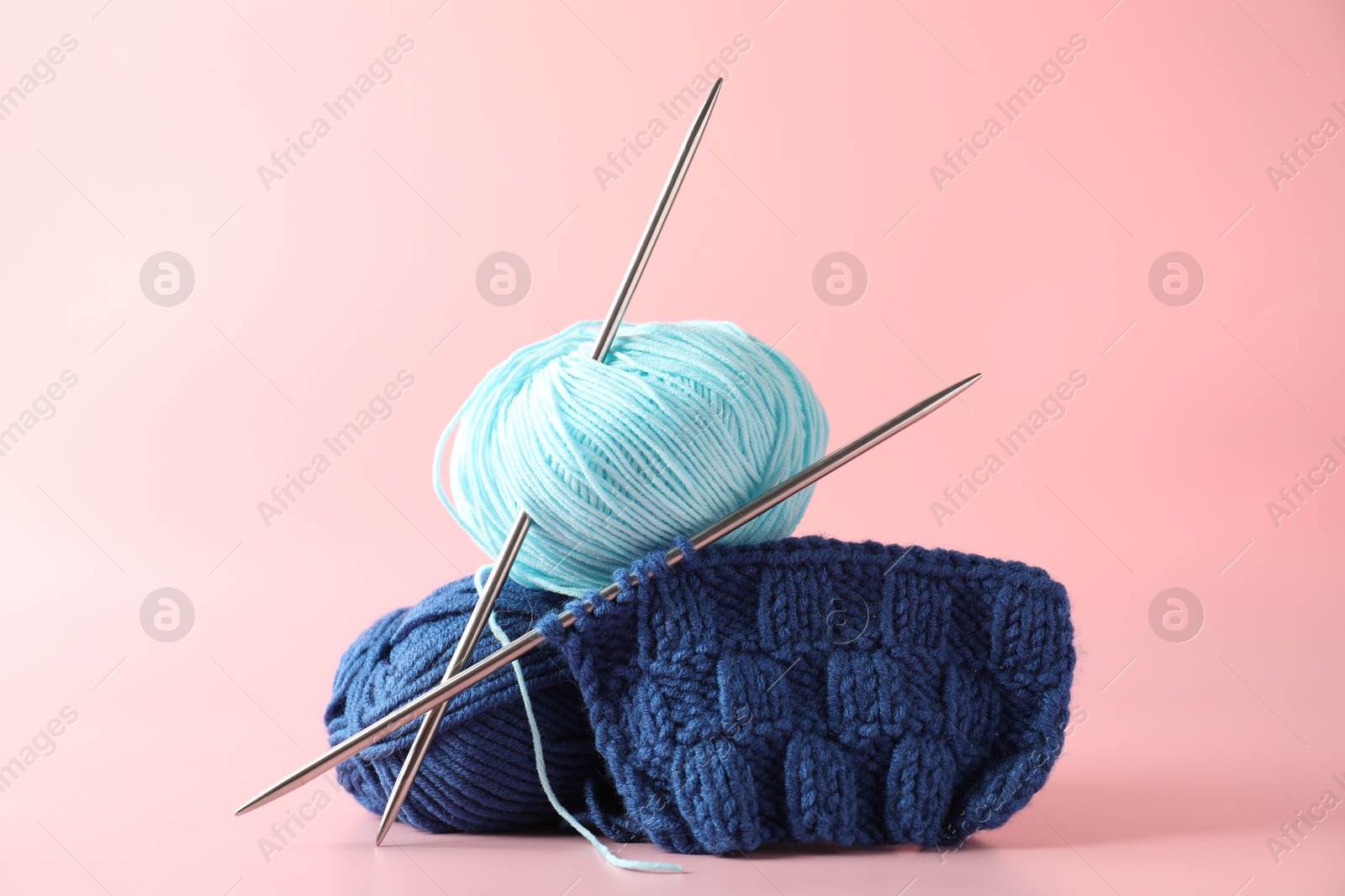 Photo of Different yarns, knitting needles and pattern sample on pink background