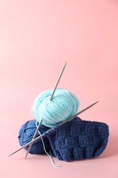 Photo of Different yarns, knitting needles and pattern sample on pink background