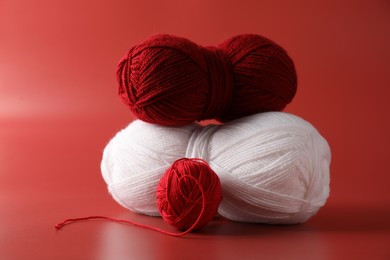 Different colorful yarns on red background. Knitting material