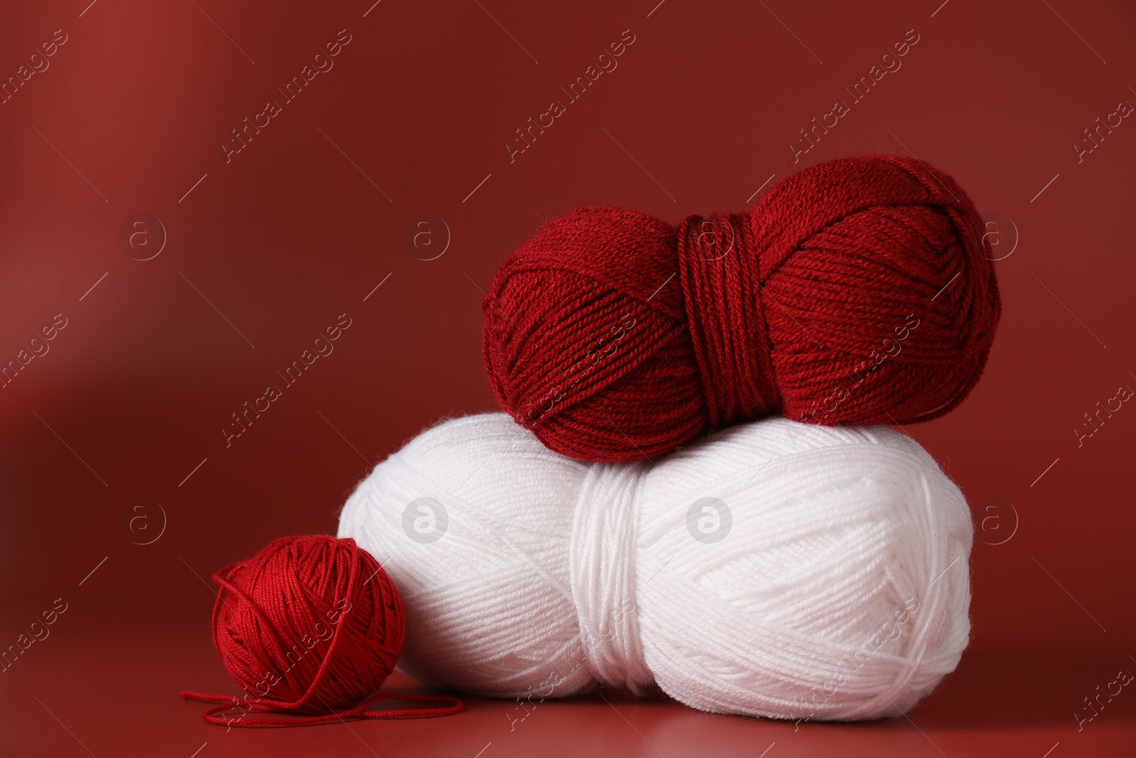 Photo of Different colorful yarns on red background. Knitting material