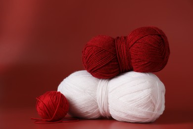 Different colorful yarns on red background. Knitting material