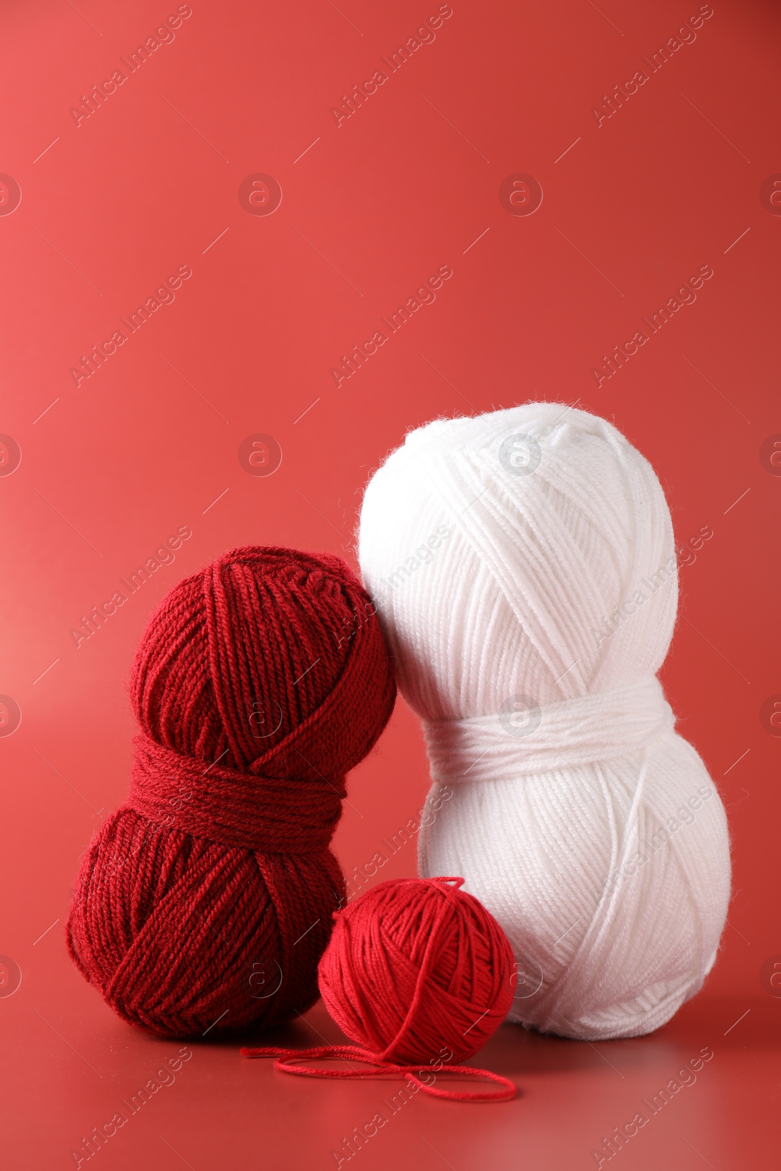 Photo of Different colorful yarns on red background. Knitting material