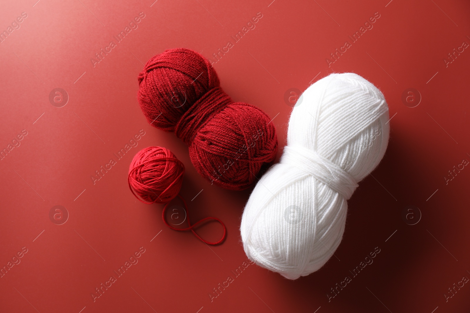 Photo of Different colorful yarns on red background, flat lay