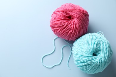 Colorful yarns on light blue background, flat lay. Space for text