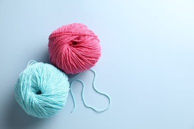 Colorful yarns on light blue background, flat lay. Space for text