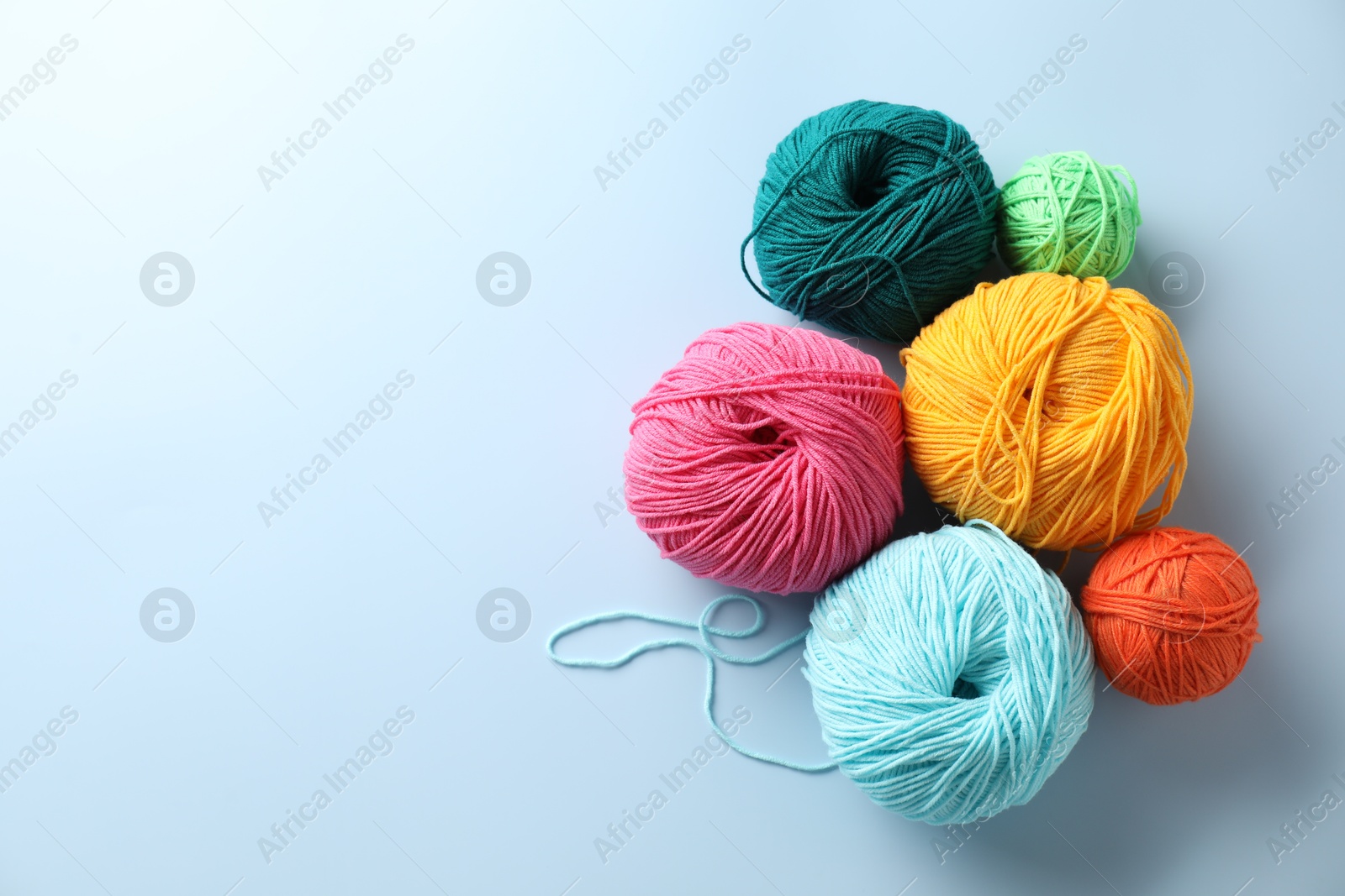 Photo of Different colorful yarns on light blue background, flat lay. Space for text