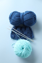 Photo of Bright yarns, knitting needles and pattern sample on light blue background, flat lay