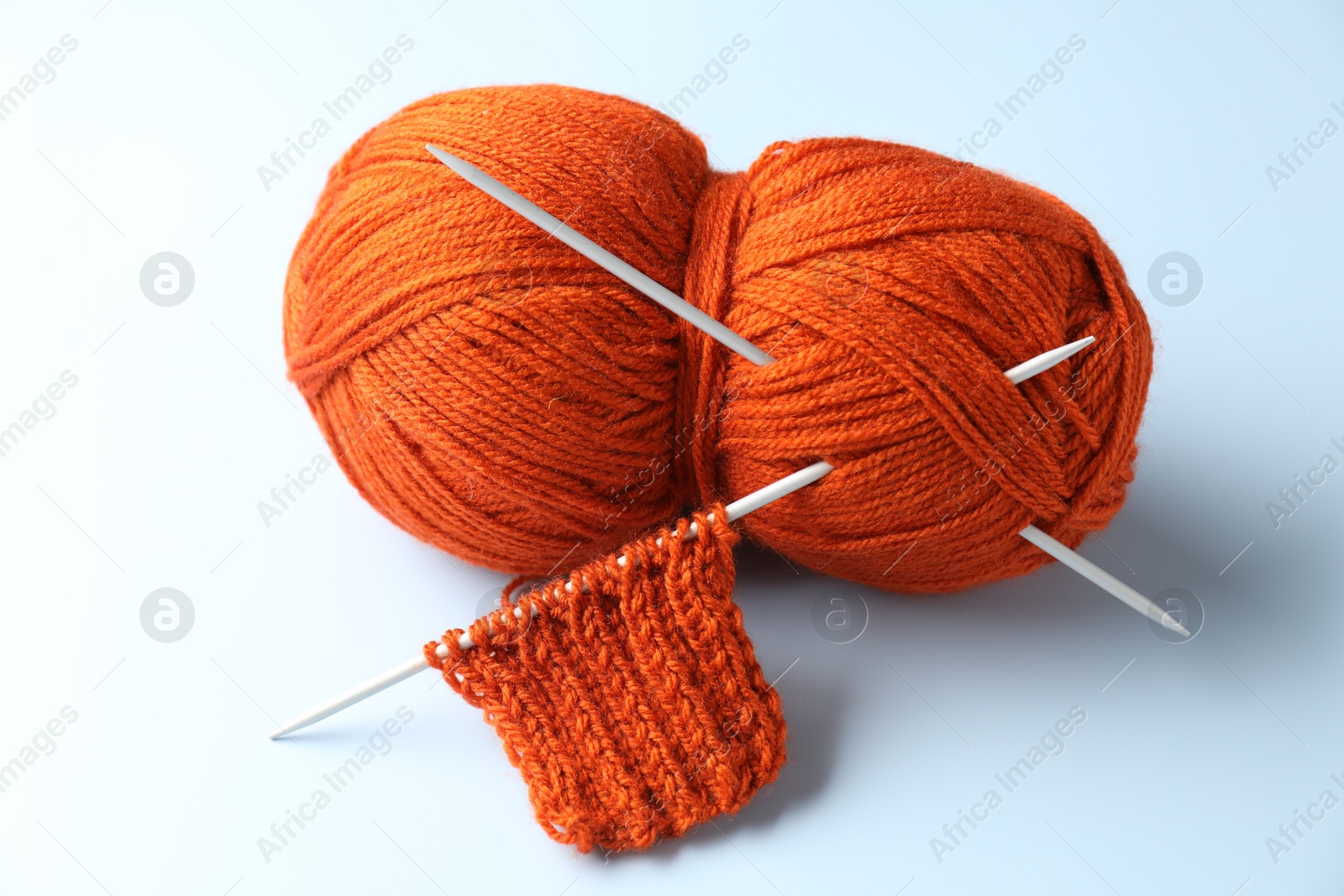 Photo of Skein of yarn, knitting needles and pattern sample on light background