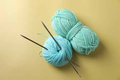 Photo of Bright yarns and knitting needles on yellow background, flat lay