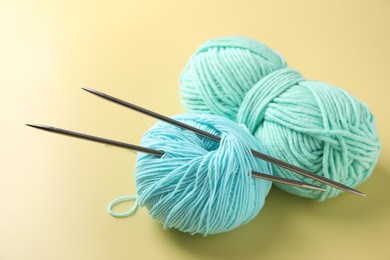 Bright yarns and knitting needles on yellow background, closeup