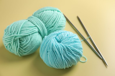 Photo of Bright yarns and knitting needles on yellow background, closeup