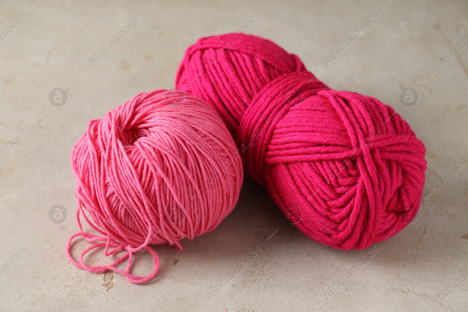 Photo of Two colorful yarns on light textured table, closeup