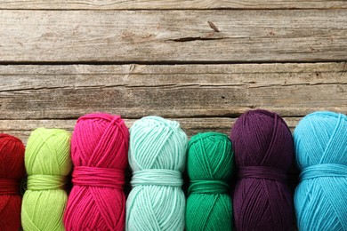 Different bright yarns on wooden table, flat lay. Space for text