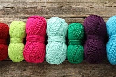 Photo of Different bright yarns on wooden table, flat lay