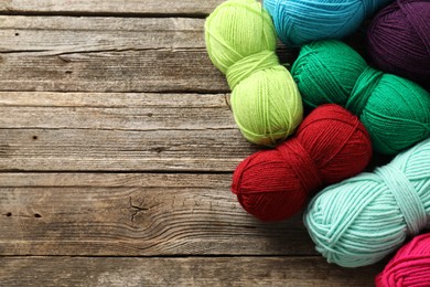 Photo of Different bright yarns on wooden table, flat lay. Space for text