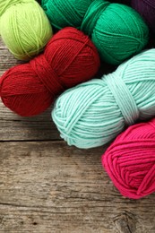 Photo of Different bright yarns on wooden table, flat lay