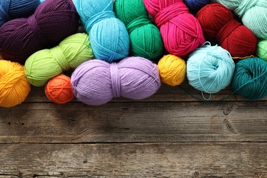 Photo of Different bright yarns on wooden table, flat lay. Space for text