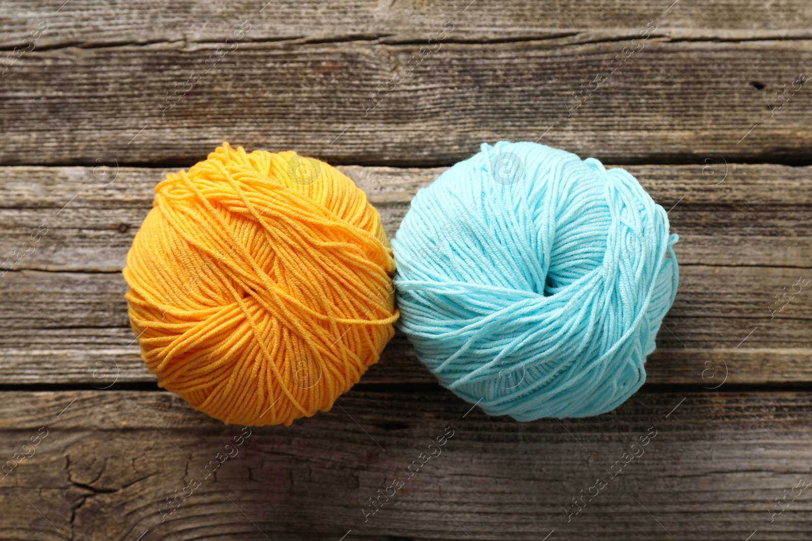 Photo of Two colorful yarns on wooden table, flat lay