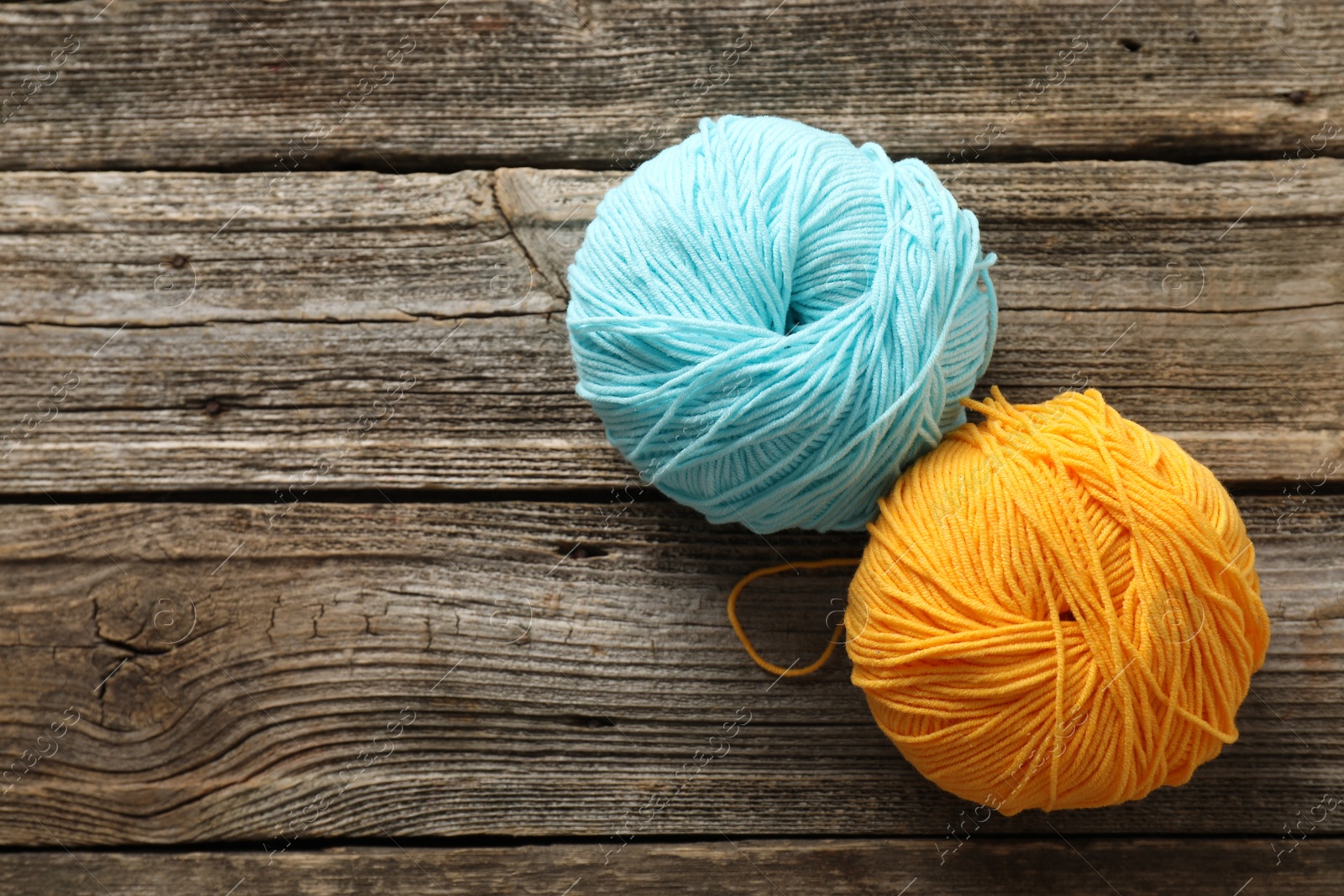 Photo of Two colorful yarns on wooden table, flat lay. Space for text