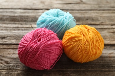 Different colorful yarns on wooden table, closeup