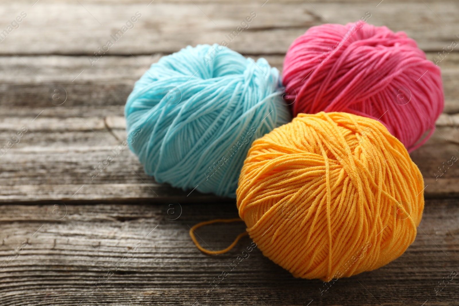 Photo of Different colorful yarns on wooden table, closeup