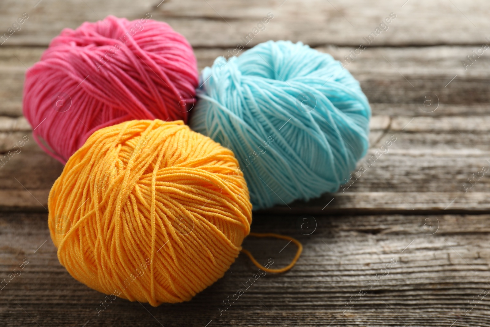 Photo of Different colorful yarns on wooden table, closeup