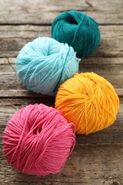 Different colorful yarns on wooden table, closeup