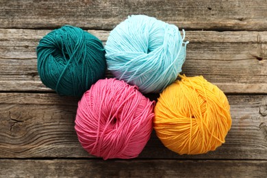 Photo of Different bright yarns on wooden table, flat lay