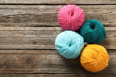 Photo of Different bright yarns on wooden table, flat lay. Space for text