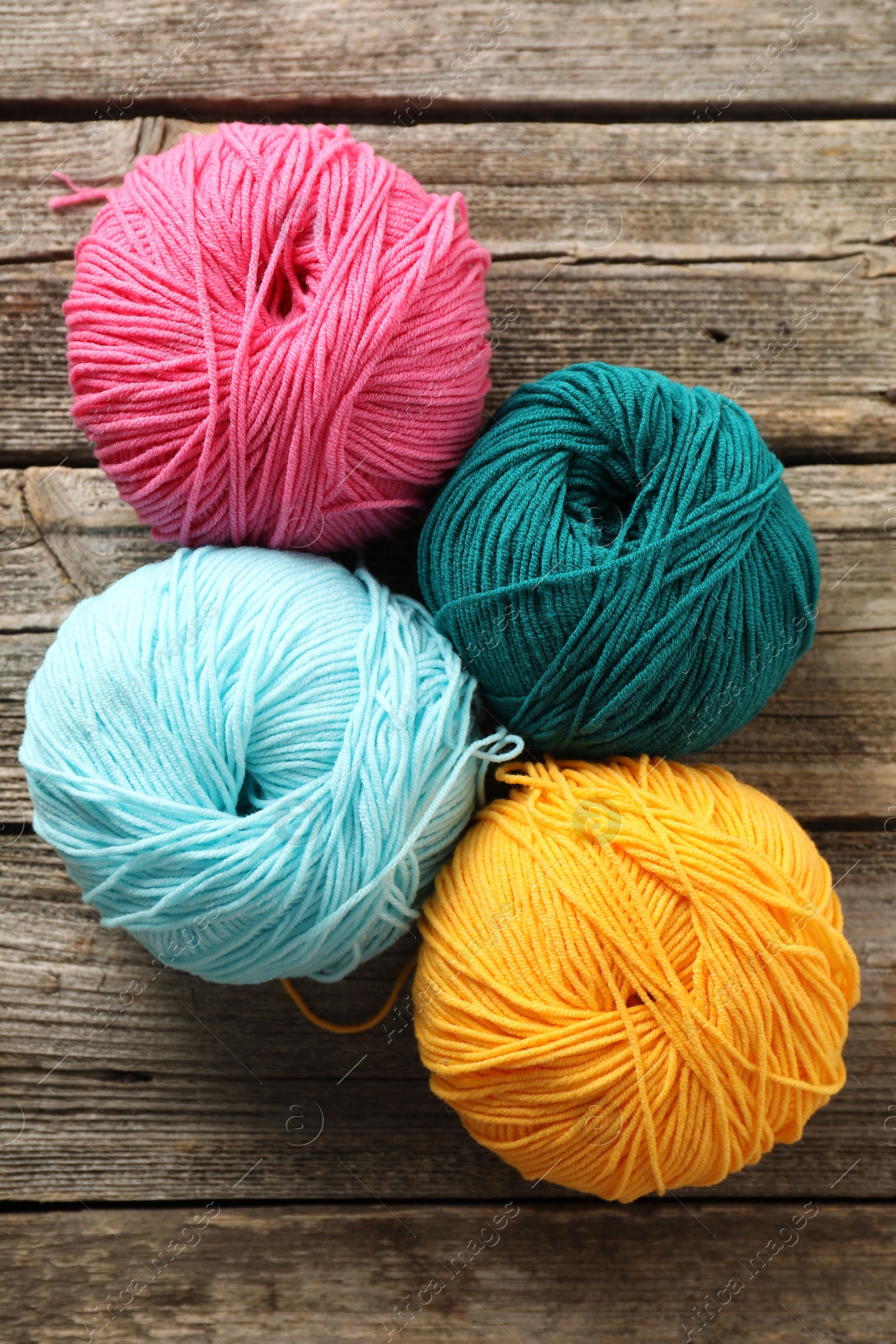 Photo of Different bright yarns on wooden table, flat lay