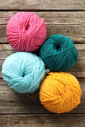 Different bright yarns on wooden table, flat lay