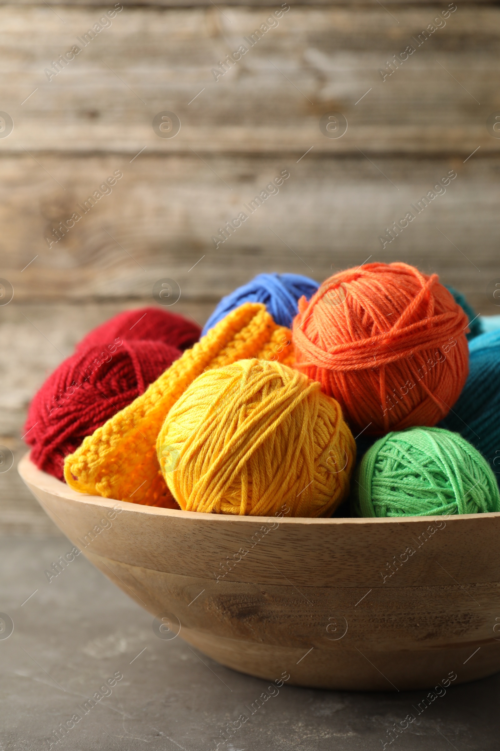 Photo of Different yarns and pattern sample in bowl on grey table, closeup