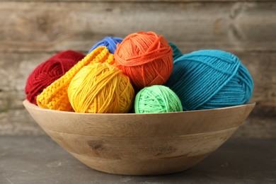 Photo of Different yarns and pattern sample in bowl on grey table, closeup