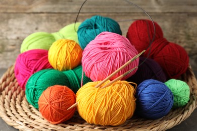 Photo of Pile of different yarns, knitting needles and wicker mat on table, closeup