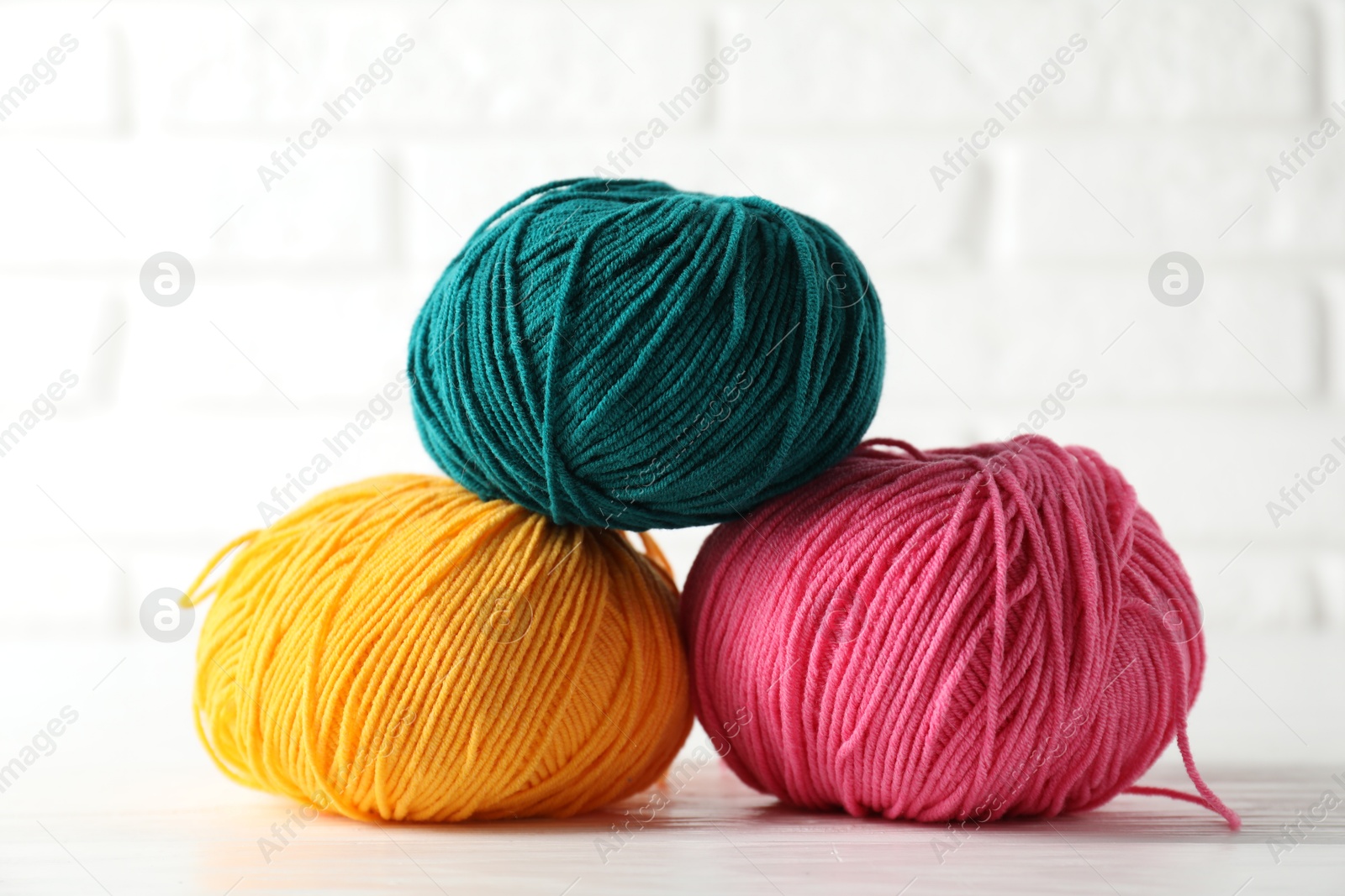 Photo of Different colorful yarns on white wooden table, closeup