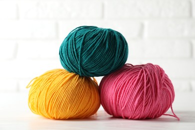 Photo of Different colorful yarns on white wooden table, closeup