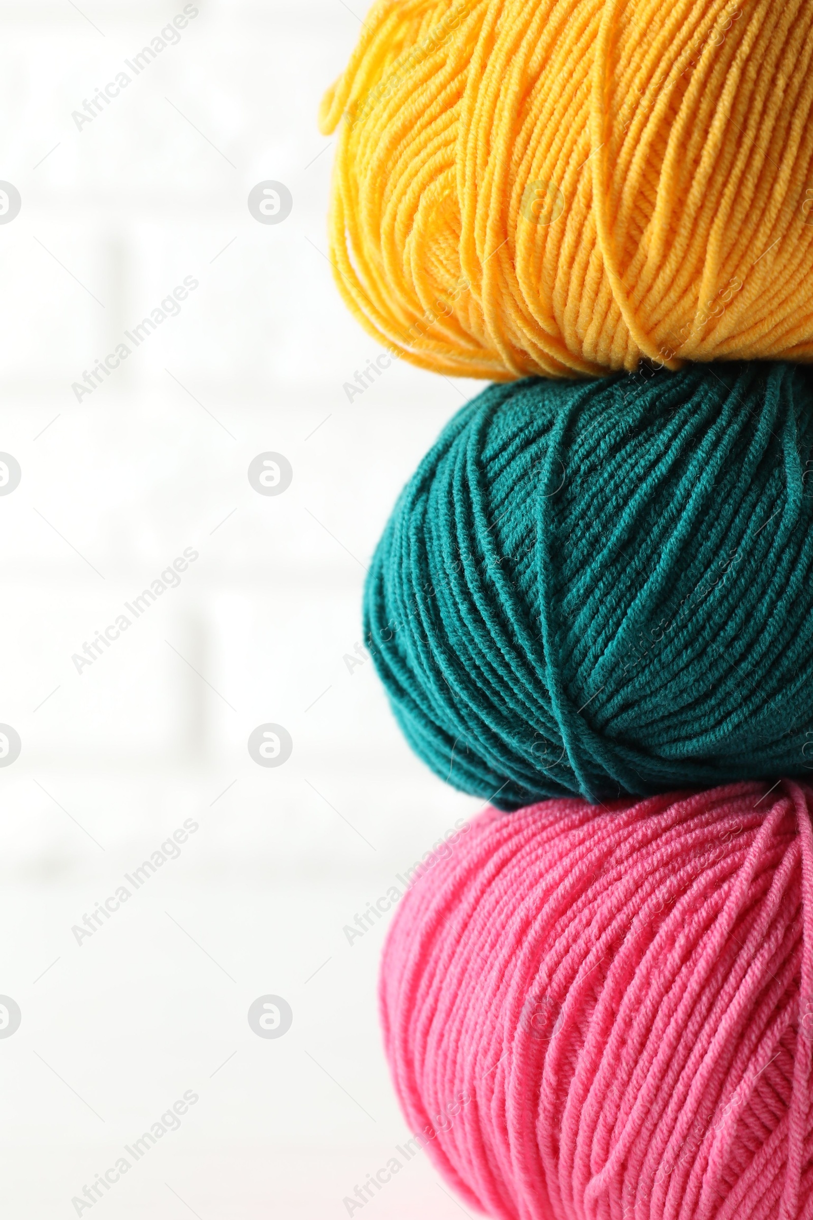 Photo of Different colorful yarns on blurred white background, closeup. Space for text