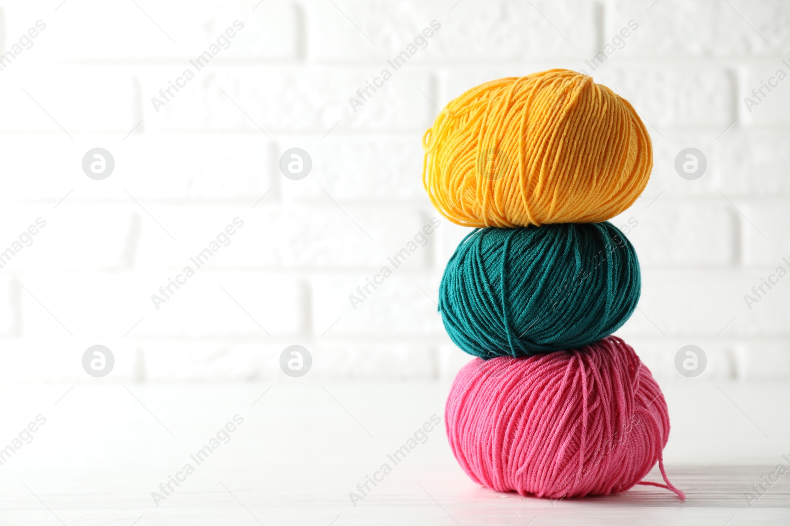 Photo of Different colorful yarns on white wooden table, closeup. Space for text