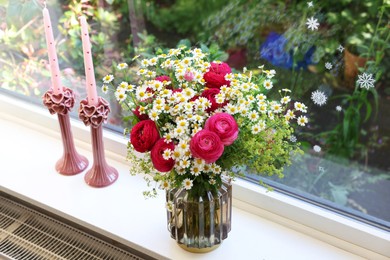 Beautiful ranunculus flowers and chamomiles in vase on windowsill indoors